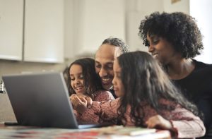 family smiles in front of a laptop